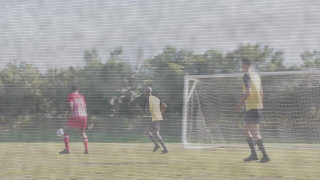 Soccer red attackers crossing from right, seeking goal, defenders clearing ball, keeper protecting