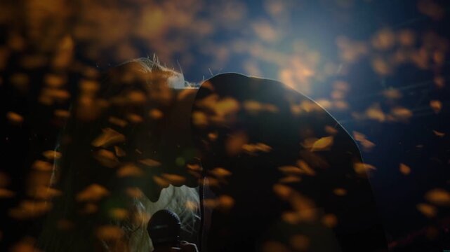 Music singer leaning to mic, tilting back and singing, climaxing with gold flecks obscuring face