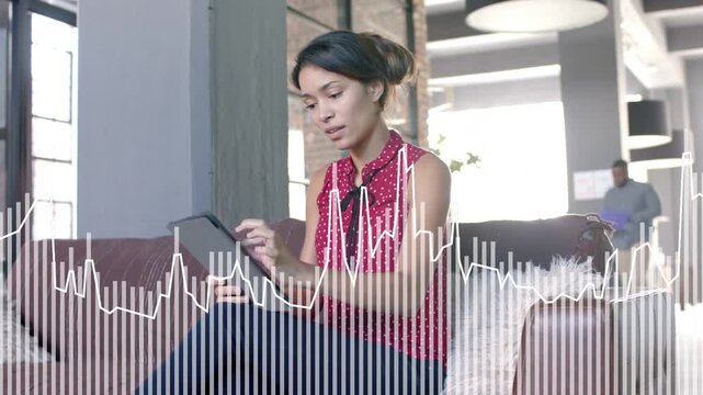 Seated woman tapping tablet reviewing UX in lounge, AV waveform reacting to taps while team passing
