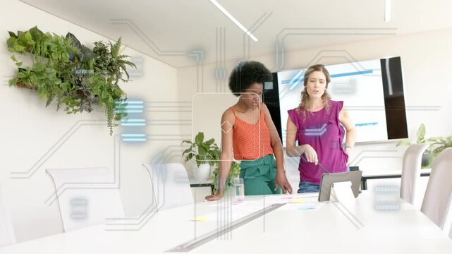 Two women leaning, purple blouse tapping tablet causing HUD overlaying, reviewing business chart