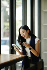 Obraz premium Businesswoman Celebrating Good News on Smartphone in Cafe