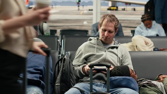 Tired tourists in airport sleeping on chairs after departure board screen showed flights got cancelled. Exhausted travelers napping on bench while waiting for delayed flight updates, camera A