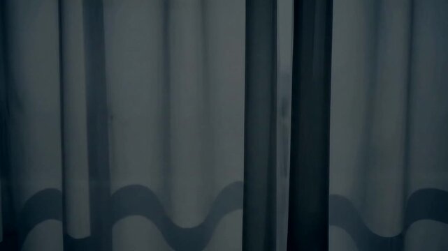 Abstract background of gray wavy fabric curtains in a dimly lit room.