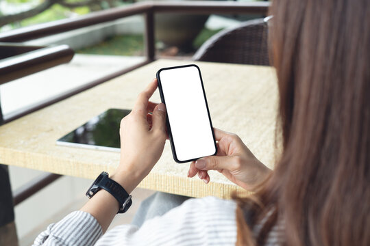 Mockup blank screen cell phone, woman hands holding smartphone with empty screen for online marketing or mobile app design. Business woman using mobile phone and working at cafe, closeup