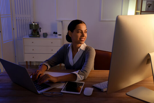 Pretty young female programmer working in office at night