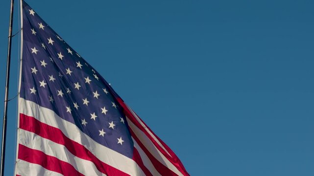 Slow Motion Seamless Loop of American Flag Waving with Copy Space Against Blue Sky