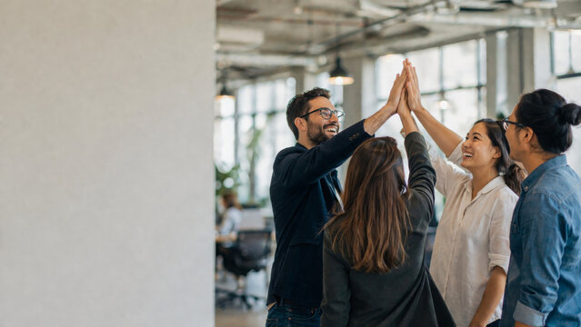 Happy business team giving high five for success