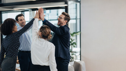 Fototapeta premium Cheerful team giving high five for business success