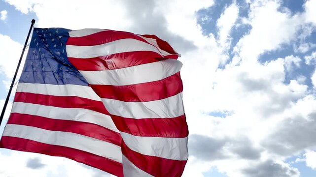 American Flag on Flagpole Waving Below Bright Cloudy Sky