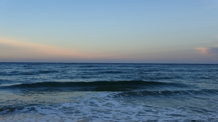 Fototapeta premium Peaceful Sea Waves at Dawn in Gangneung. Gentle white foam from waves washing ashore under a soft, pastel-colored morning sky. A serene and relaxing coastal scene at the East Sea.