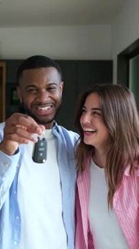 An excited young couple joyfully shows off the keys to their new car, celebrating their recent purchase and future adventures together.
