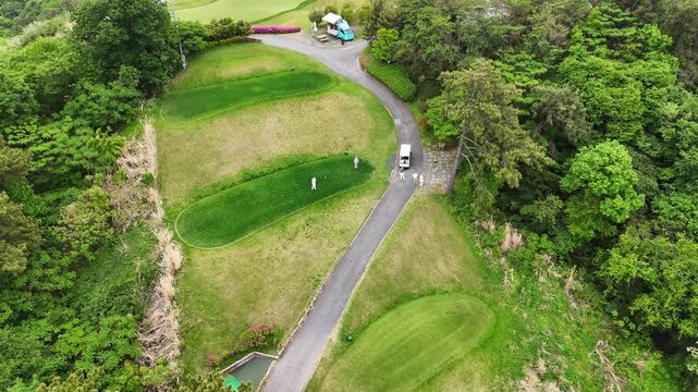 Aerial drone view of golf course with multiple putting greens and players. Top view of fairway, cart path and outdoor sport activity in nature
