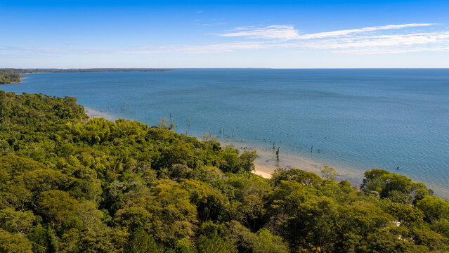 Aerial view of remote shoreline and forest along Parana River reservoir, ideal for travel and nature content.