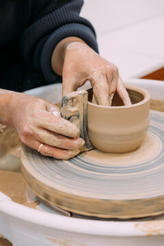 Manufacturing earthenware. Hands shaping clay. Unrecognizable experienced artisan woman working with raw using tool electric wheel.