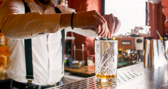 Fresh cocktail. Alcohol beverage. Unrecognizable professional male barman hands serving decorating drink on bar counter.
