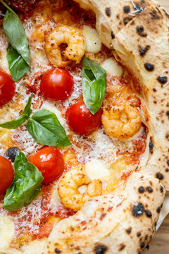 Neapolitan pizza. Italian fast food. Melted cheese mozzarella with fresh tomatoes sauce green basil leaves garnish dish with shrimp.