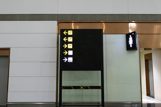 Billboard black flight arrival show symbol and arrows provide directions Gates by background image of airport building wall. Departure timetable check in modern terminal departure. Screens templates.