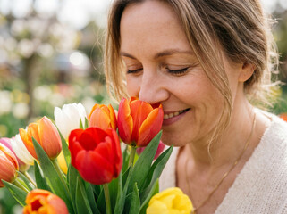 Fototapeta premium Happy Young Woman Smelling a Bouquet of Fresh Spring Tulips