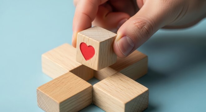 Hand placing wooden block with red heart on top of stack
