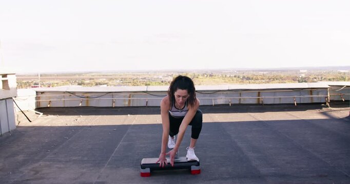 Fitness exercising. Healthy lifestyle. Flexible athletic woman enjoying professional sport performing outdoor active training on rooftop.