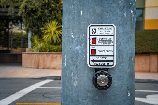 Pedestrian crossing signal button on a metal pole with instructions