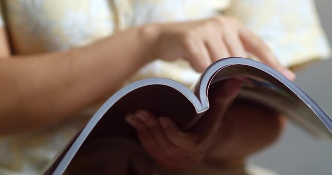 A person enjoys exploring a magazine absorbed in interesting content at home.