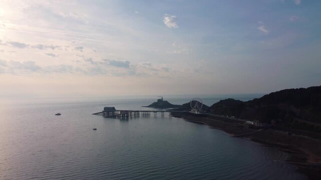 Aerial of Mumbles Pier and Lighthouse at Sunrise. Golden Morning Light Over Bay. Perfect for tourism, travel documentaries. Wales, UK. 4K.