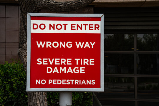 Red and white sign warns of wrong way and severe tire damage