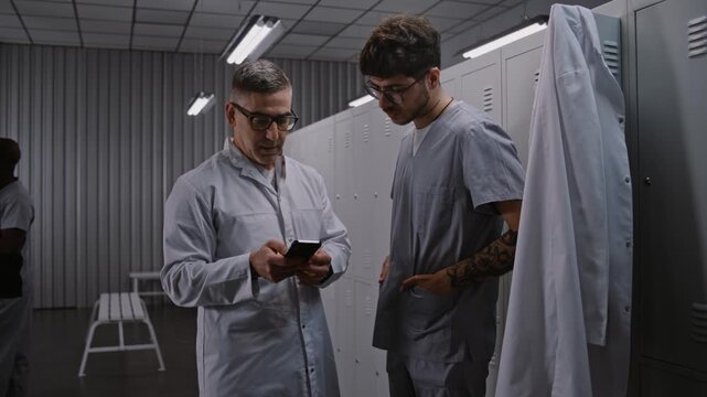 Two Focused Male Surgeons Use Smartphone App Review and Discuss Digital Patient Scans and Preoperative Surgical Plans Before Difficult Procedure. Medical Technology and Planning Concept in Hospital.