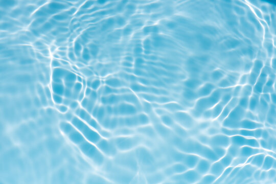 Blue water with ripples on the surface. Defocus blurred transparent blue colored clear calm water surface texture with splashes and bubbles. Water waves with shining pattern texture background.