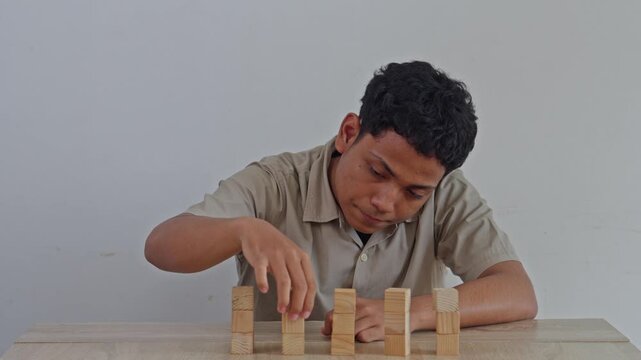 Young man with OCD meticulously arranging wooden blocks in perfect line