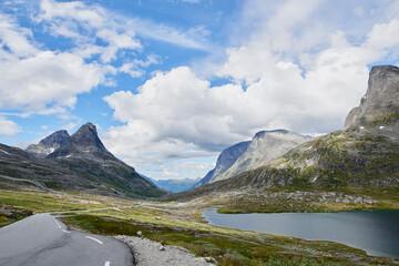 Fototapeta premium Blue sky, mountain and clouds with road of landscape, valley or beautiful climate in nature. Empty, space and wilderness of river stream or street with greenery, snow or lake for outdoor destination