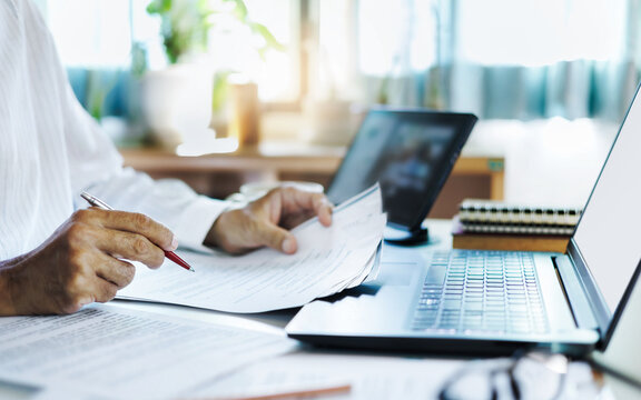 close up shot, asian businessman using laptop and tablet working online checking ducuments and business contract to start new business e-commerce