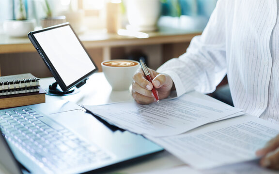 close up shot, asian businessman using laptop and tablet working online checking ducuments and business contract to start new business e-commerce