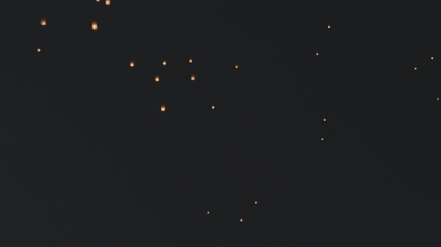 Glowing sky lantern floating up in the dark night sky. Traditional Asian light festival, celebration and spiritual wishing concept. Loy Krathong, Yi Peng or Diwali cultural celebration background.
