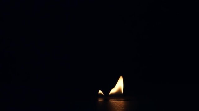 Single realistic fire flame burning, flickering, and gradually dying out isolated on a pure black background for VFX overlay and compositing.