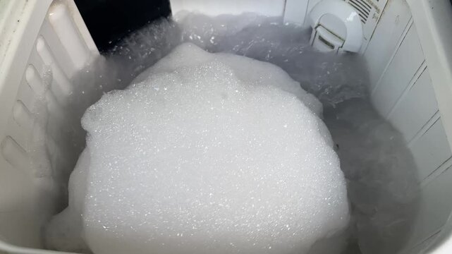 Washing Machine Filled With Excessive White Soap Foam and Bubbles