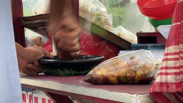Street food vendor grinding ingredients with mortar and pestle