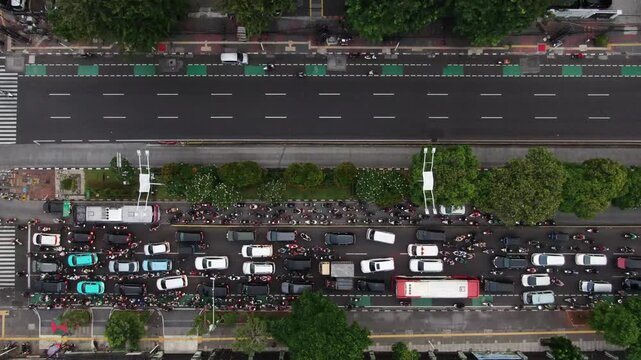 Aerial Top View of Stark Traffic Contrast on City Avenue. One Side Facing Heavy Congestion with Motorcycles and Buses while the Other Lane is Empty. Concept of Urban Mobility and Rush Hour Traffic