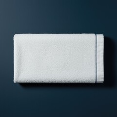 Obraz premium White cotton towel with blue stitching resting on a dark navy surface for home textile catalog, bathroom product mockup and hospitality lifestyle branding
