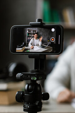 A man is recording a video on his smartphone while giving an okay gesture, suggesting a positive message or tutorial