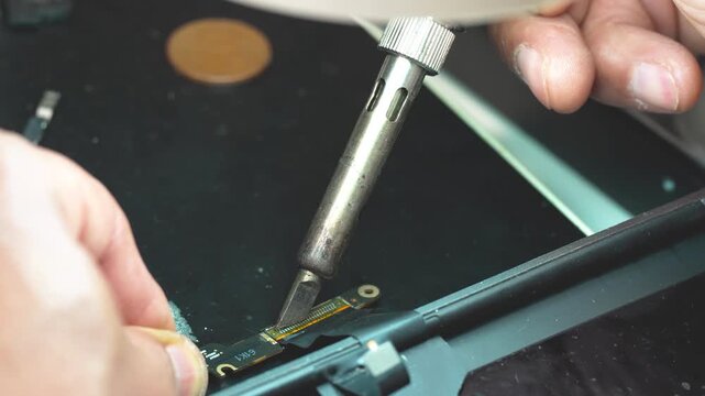 Close up of technician repairing laptop video connector with precision soldering tools workbench