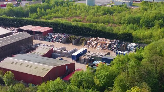 Sideways Aerial of Modern Recycling Center and Sorting Facility. Sustainable waste management, showing neatly stacked bales of paper, plastic, and aluminum and warehouse. Industrial-scale recycling.