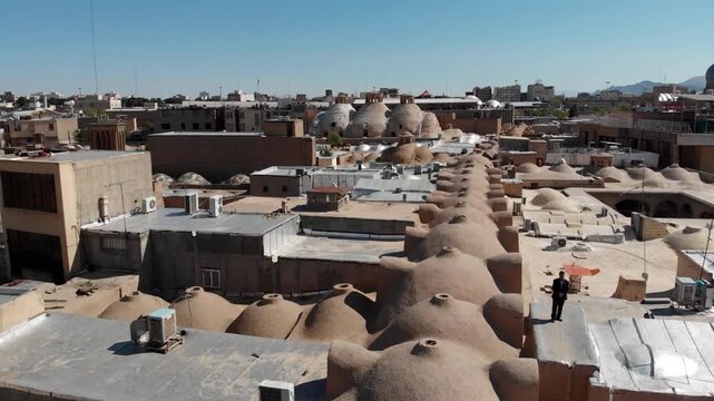  Panoramic view of traditional mud-brick rooftops and domes in an ancient desert town. This footage shows the unique urban landscape and historical architecture of a Middle Eastern city area. 
