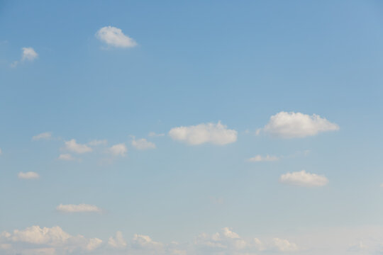 Wispy white clouds scattered across a vast pale blue sky on a bright day
