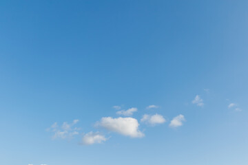 Fototapeta premium Minimalist view of a few small white clouds in the lower third of a vast clear blue sky