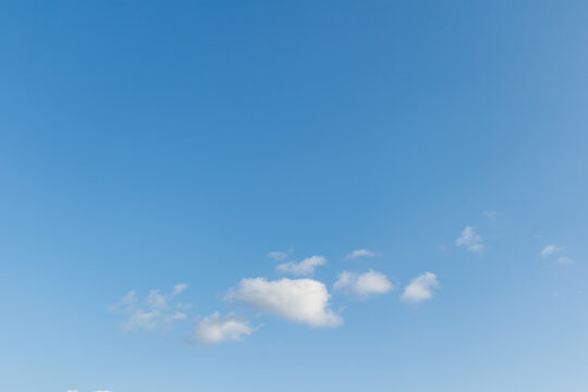 Minimalist view of a few small white clouds in the lower third of a vast clear blue sky