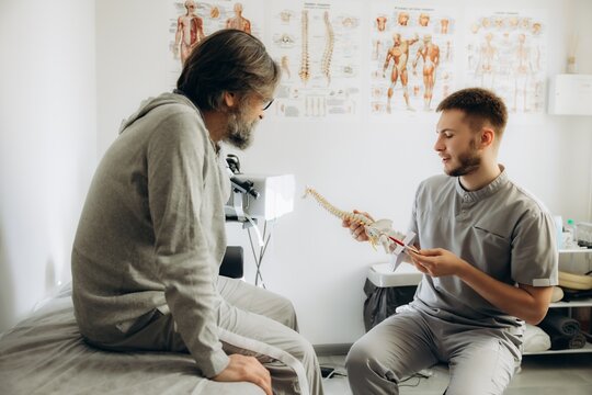 Physiotherapist explaining spine model to patient during consultation