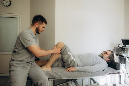 Physical therapist helping senior man with knee rehabilitation