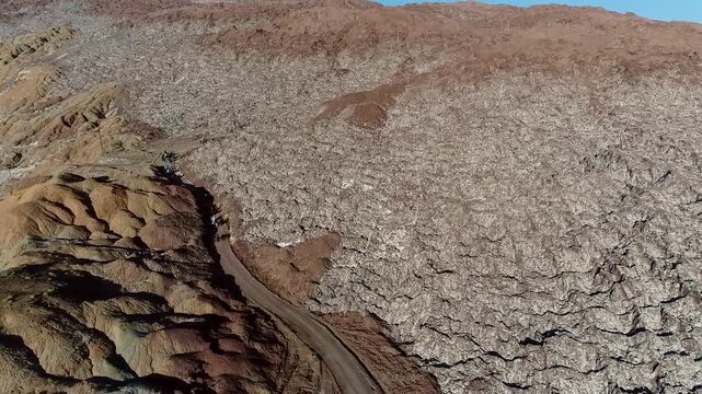  Dry and cracked salt flats or desert earth viewed from above, highlighting the patterns of dehydration and the harsh beauty of arid environments under a clear and bright afternoon sunlight. 